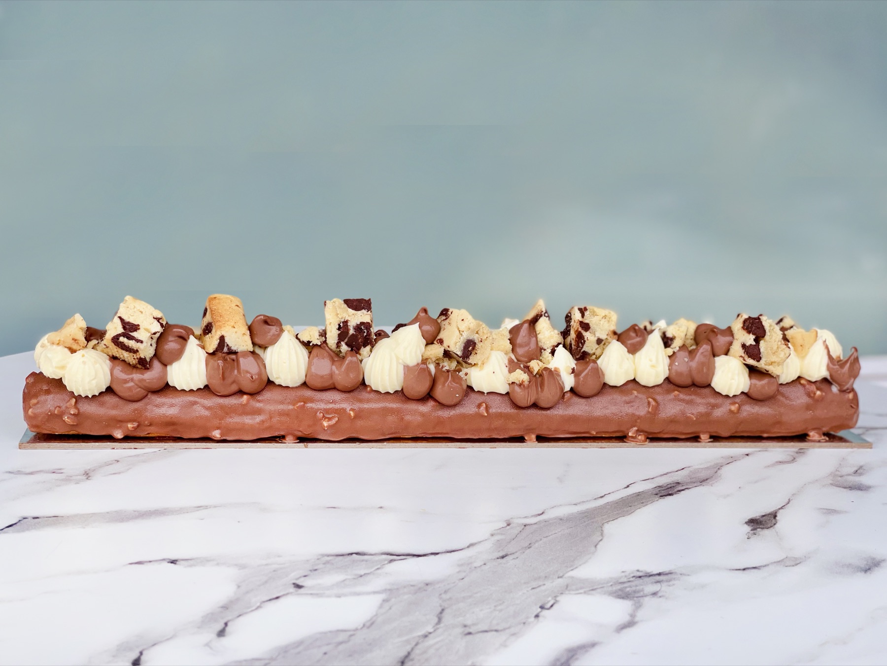Chocolate-coated long éclair with cream and cookie pieces