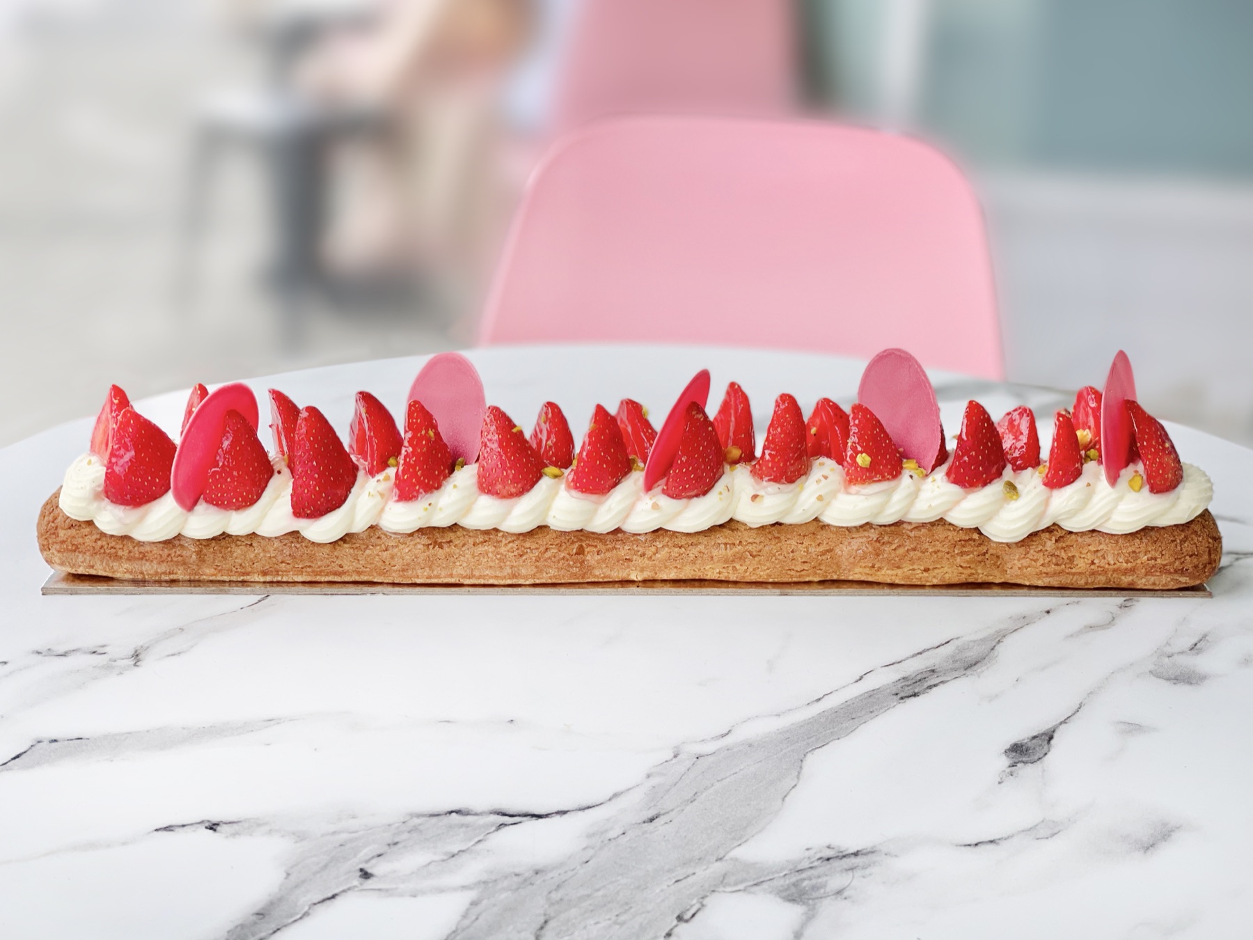 Extra-long éclair with piped cream and strawberries