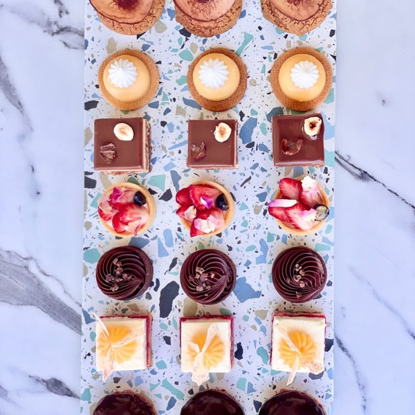 A tray of sweet canapés: fruit tartlets, chocolate squares and coffee cups