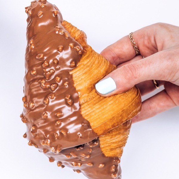 A hazelnut chocolate croissant held in one hand