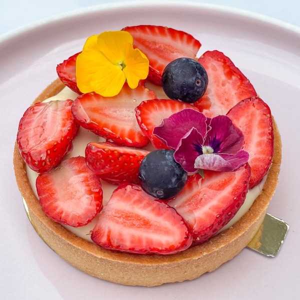 A strawberry and blueberry fruit tart with edible flowers